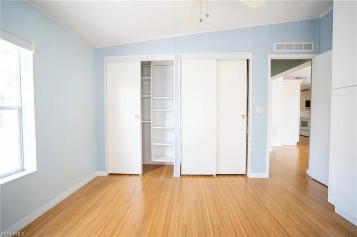 Unfurnished bedroom featuring light wood-style flooring, ornamental molding, and two closets