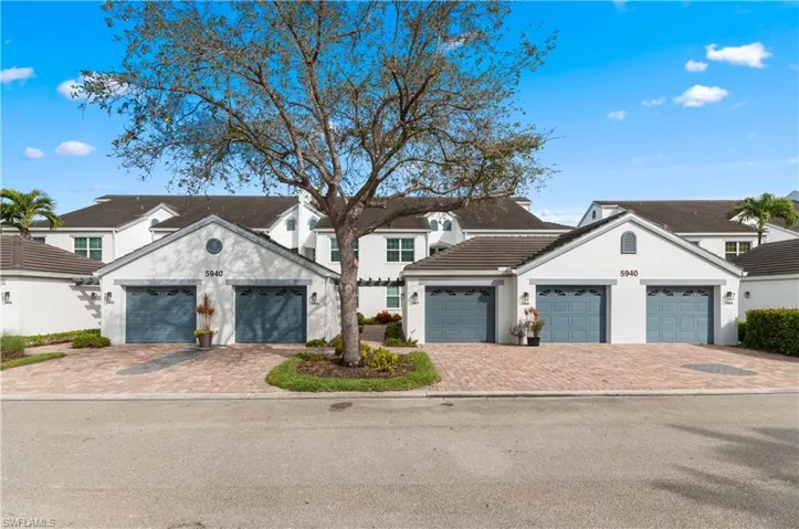 View of front facade with stucco siding, driveway, and a tiled roof