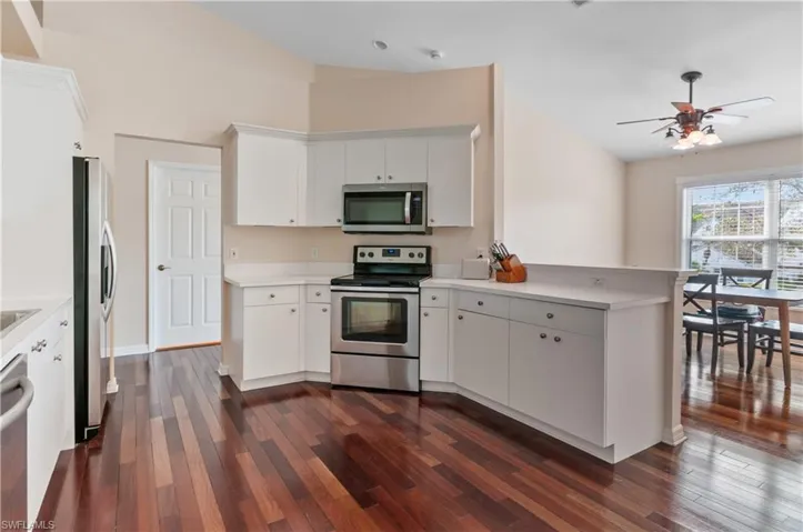 Kitchen with lofted ceiling, appliances with stainless steel finishes, white cabinets, and light countertops