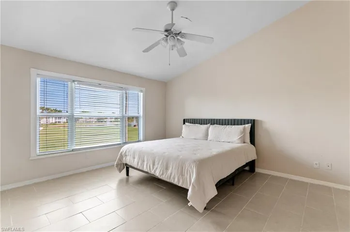 Bedroom with vaulted ceiling, a ceiling fan, and light tile patterned flooring