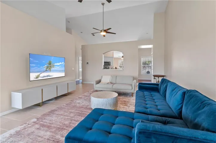 Tiled living room featuring high vaulted ceiling, a ceiling fan, and arched walkways