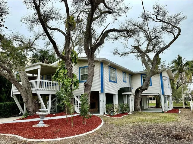 Front of Fort Myers Beach home.  Gulf Access home!  New mulch and landscaping just updated, all the trees and bushes just trimmed. You can drive your boat and trailer right under the home and back it up into the canal to launch from your granfathered in personal boat ramp.