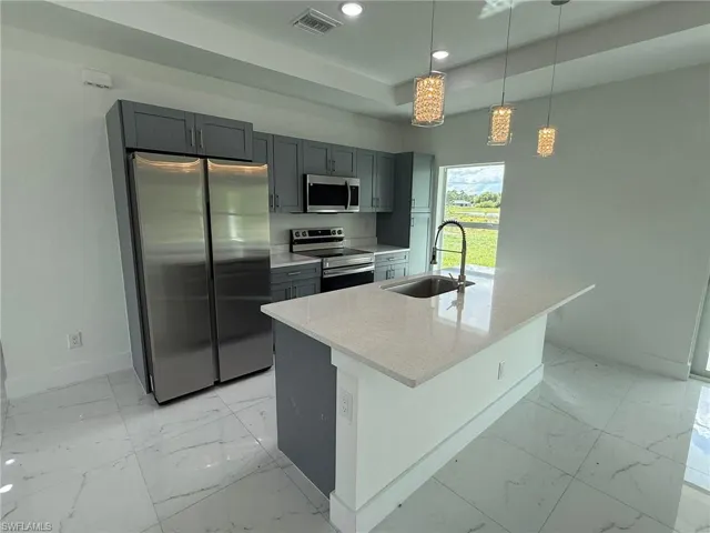 Kitchen featuring light marble finish floors, stainless steel appliances, recessed lighting, and gray cabinets