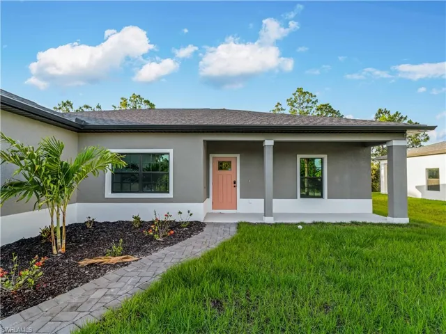 Ranch-style house featuring stucco siding, a front yard, covered porch, and roof with shingles