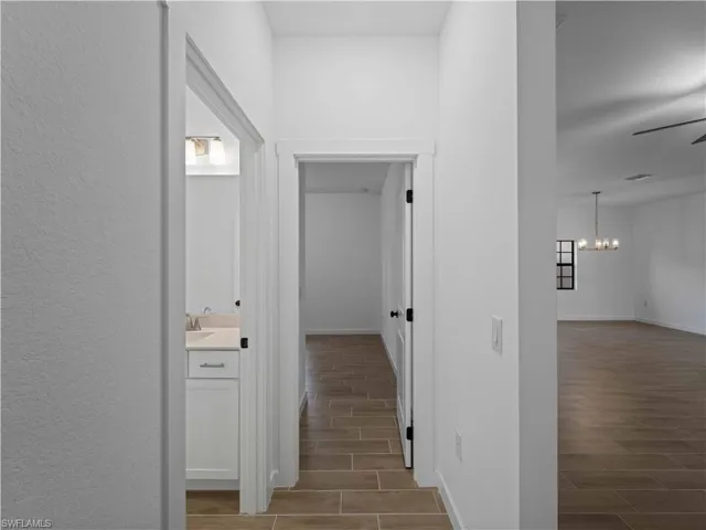 Hall featuring wood tiled floors, a chandelier, baseboards, and a sink