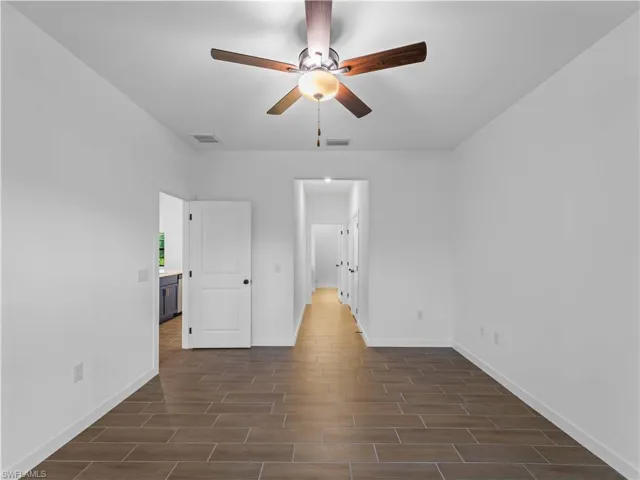 Unfurnished bedroom with baseboards, dark wood-type flooring, and ceiling fan