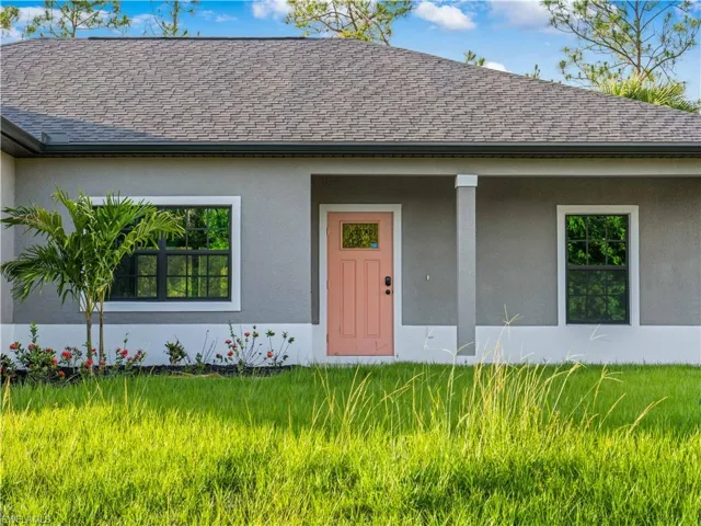 View of front of house featuring a shingled roof and stucco siding