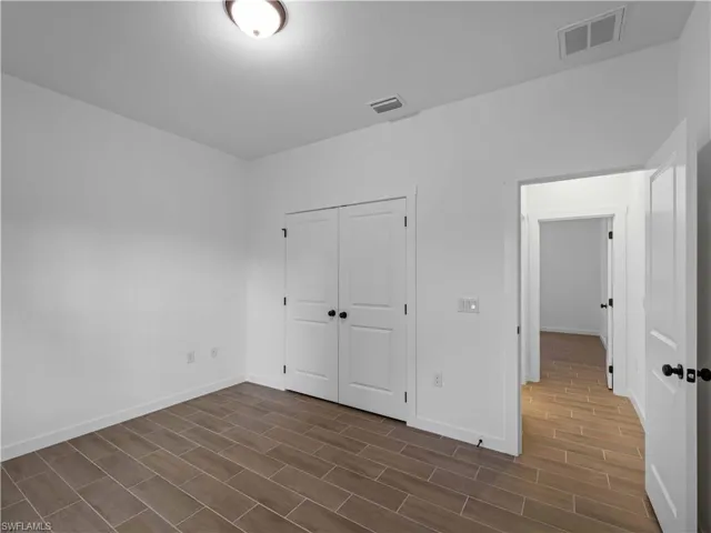 Unfurnished bedroom with dark wood-style flooring, baseboards, and a closet