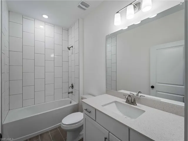 Full bathroom featuring toilet, tub / shower combination, vanity, and wood tiled floors