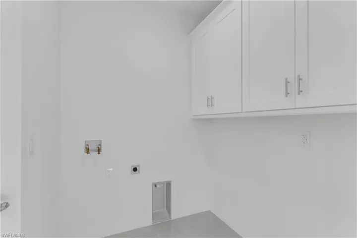 Clothes washing area with electric dryer hookup, cabinets, and hookup for a washing machine
