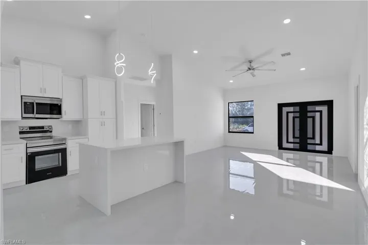 Kitchen with appliances with stainless steel finishes, tasteful backsplash, ceiling fan, white cabinets, and hanging light fixtures