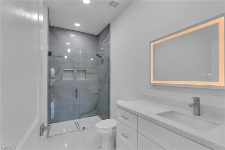 Bathroom featuring vanity, toilet, and a shower with door