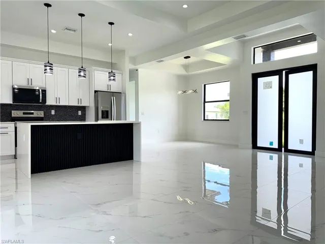 Kitchen with appliances with stainless steel finishes, open floor plan, a center island, backsplash, and white cabinetry