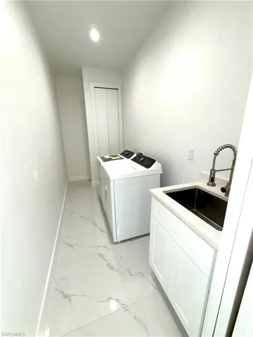 Washroom featuring independent washer and dryer, light marble finish flooring, recessed lighting, and cabinet space