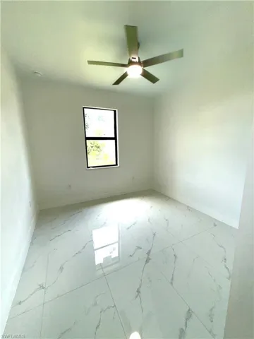 Spare room featuring light marble finish flooring and ceiling fan