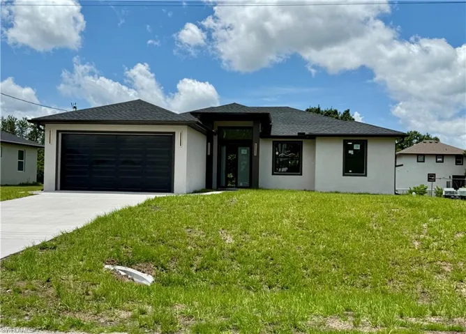 Prairie-style house featuring stucco siding, driveway, a garage, and a front yard