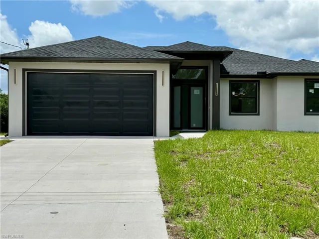 Prairie-style house featuring concrete driveway, stucco siding, an attached garage, a front yard, and a shingled roof