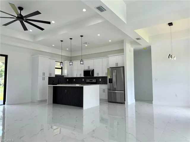 Kitchen with stainless steel appliances, a center island, a tray ceiling, decorative backsplash, and recessed lighting