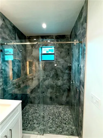 Bathroom with vanity, a marble finish shower, and recessed lighting
