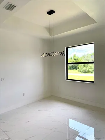 Empty room featuring marble look tile flooring and a raised ceiling