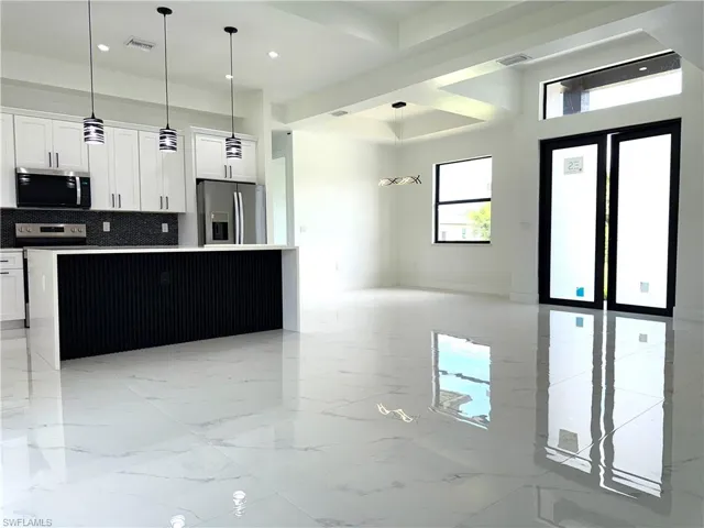 Kitchen with appliances with stainless steel finishes, open floor plan, tasteful backsplash, white cabinetry, and recessed lighting