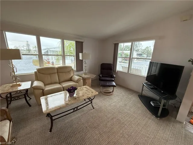 Carpeted living room featuring lofted ceiling