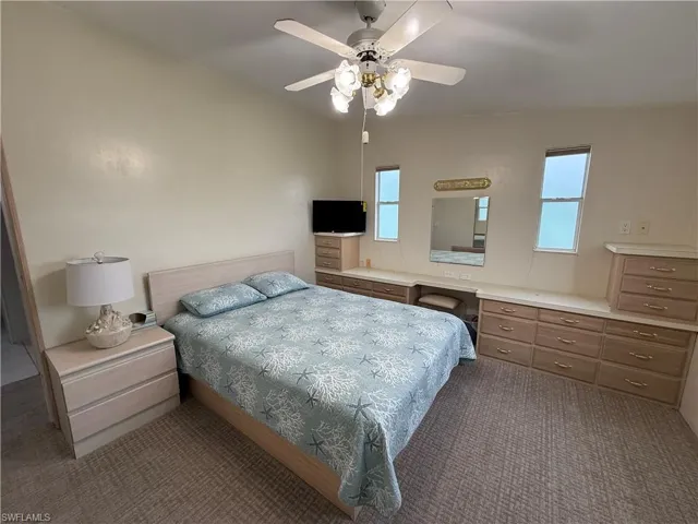 Carpeted bedroom featuring ceiling fan and built in desk