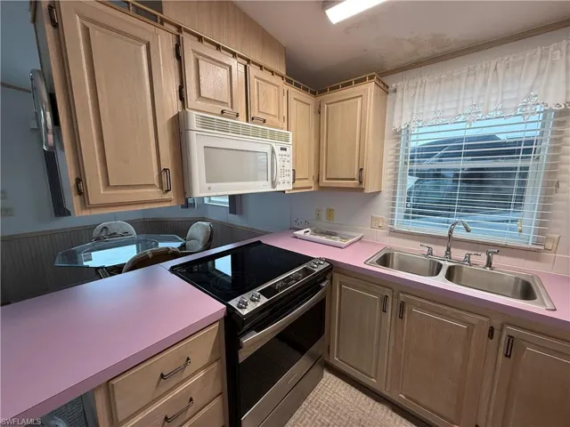 Kitchen with stainless steel range with electric stovetop and sink