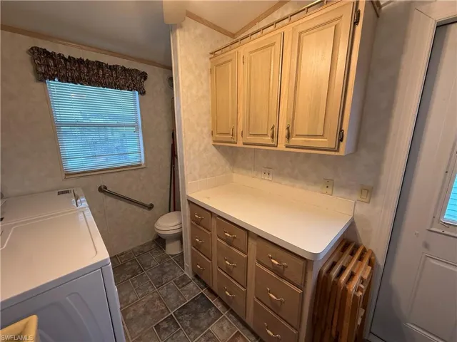 Bathroom featuring washer and clothes dryer, radiator heating unit, and toilet