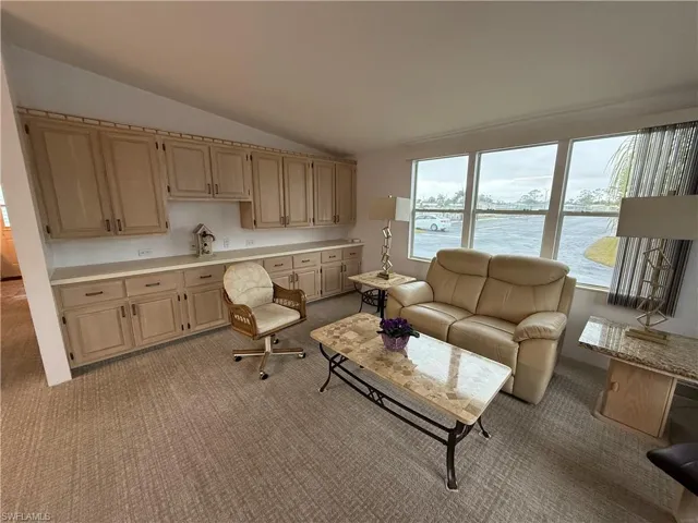 Carpeted living room with lofted ceiling and a water view