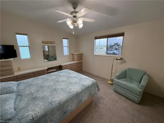 Bedroom with ceiling fan, light colored carpet, and lofted ceiling