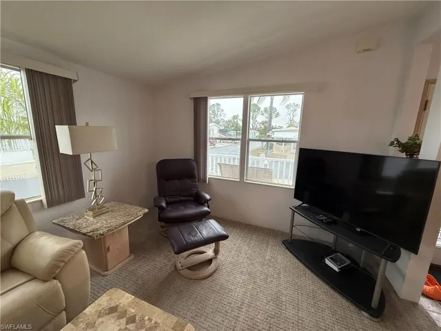 Living area featuring light carpet and vaulted ceiling