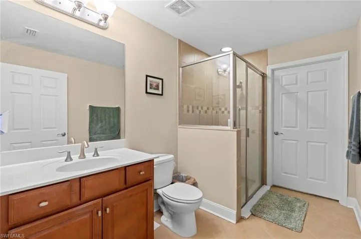 Bathroom with light tile patterned floors, vanity, and a shower stall