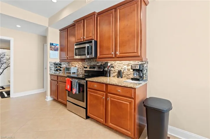Kitchen with appliances with stainless steel finishes, decorative backsplash, light stone counters, light tile patterned floors, and recessed lighting