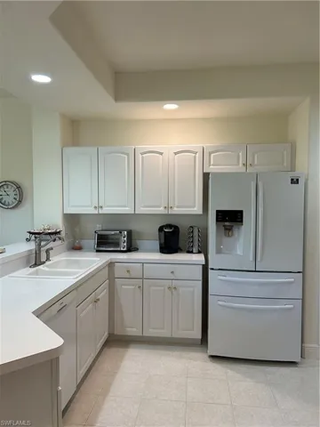 Kitchen featuring refrigerator, sink, dishwasher, and light tile floors