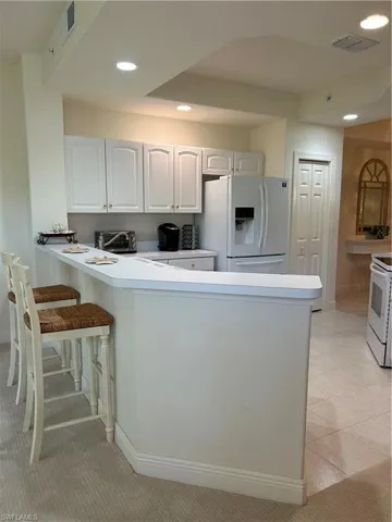 Kitchen with light carpet, fridge, and kitchen peninsula