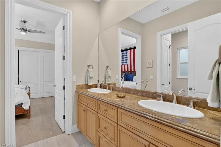Full bathroom with connected bathroom, double vanity, light wood-style flooring, and a ceiling fan