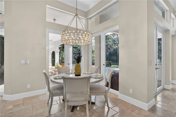 Dining room featuring crown molding, stone tile floors, and a chandelier