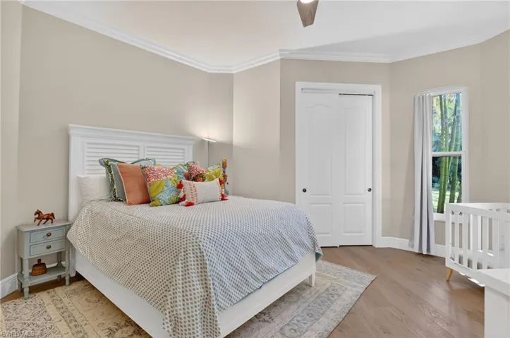 Bedroom featuring a closet, light wood-style floors, crown molding, and a ceiling fan