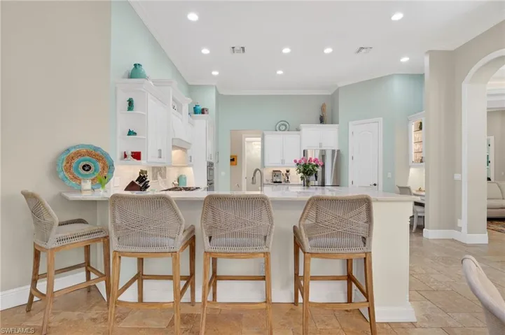 Kitchen featuring recessed lighting, white cabinetry, a peninsula, a breakfast bar area, and decorative backsplash