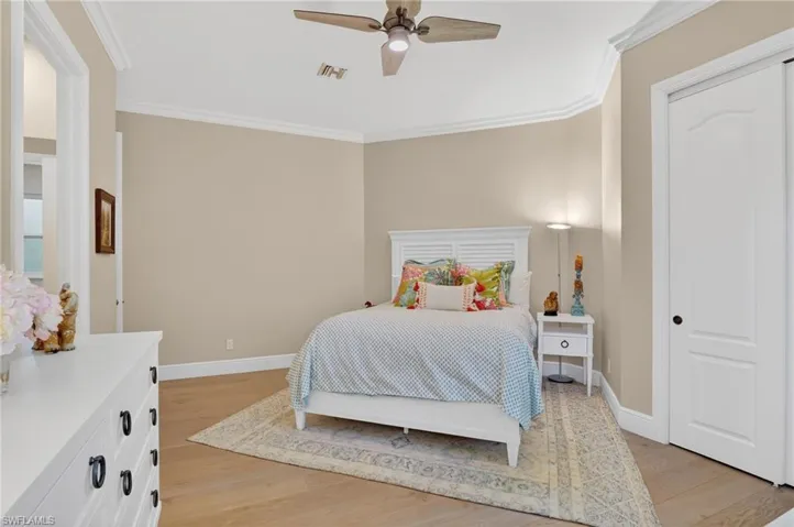 Bedroom featuring ornamental molding, light wood-style floors, ceiling fan, and a closet