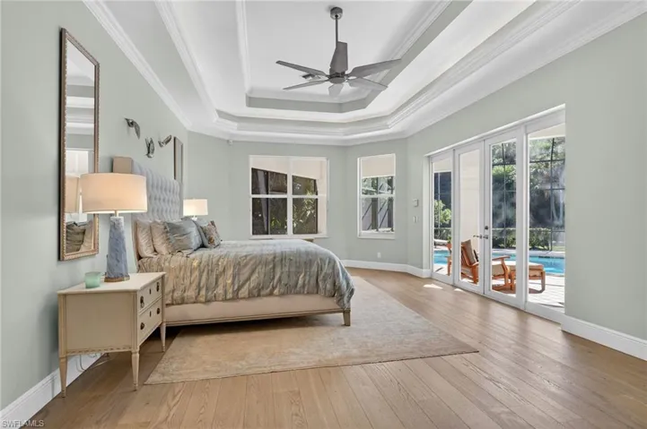 Bedroom featuring access to exterior, ornamental molding, ceiling fan, light wood-style flooring, and a tray ceiling