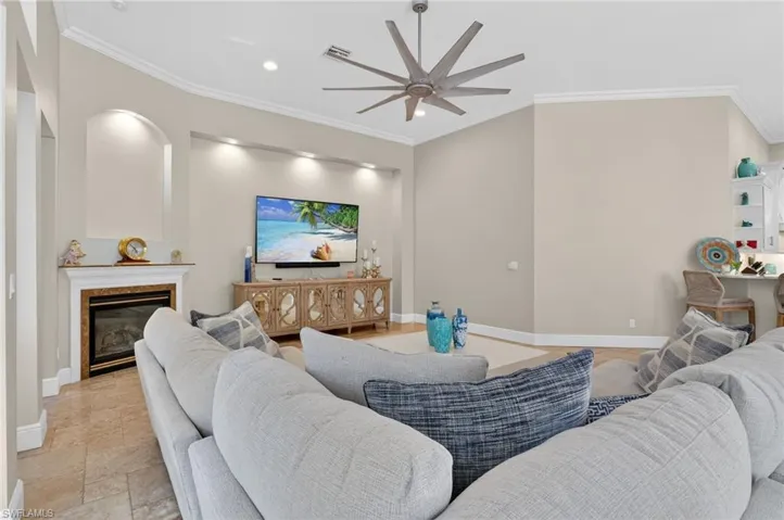 Living area featuring ornamental molding, a high end fireplace, a ceiling fan, recessed lighting, and stone tile floors
