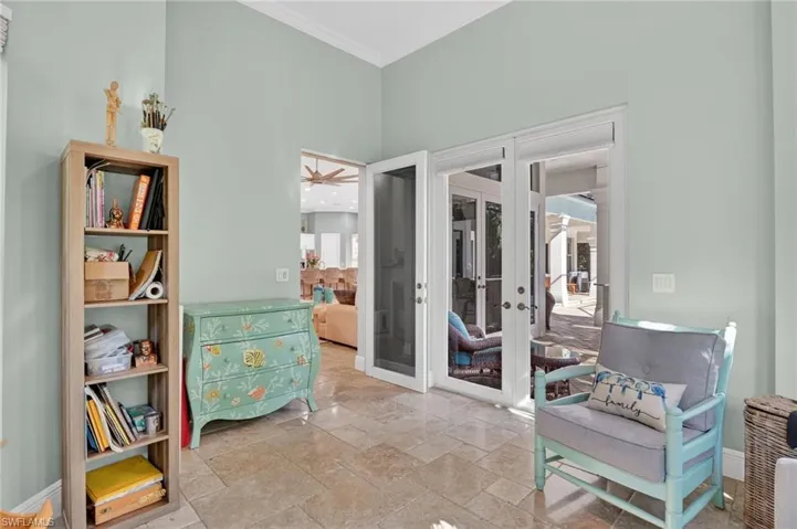 Sitting room with french doors, crown molding, stone tile floors, ceiling fan, and a high ceiling