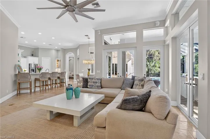 Living area featuring crown molding, french doors, a ceiling fan, arched walkways, and a chandelier