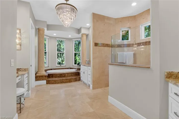 Bathroom with vanity, a bath, decorative columns, and plenty of natural light