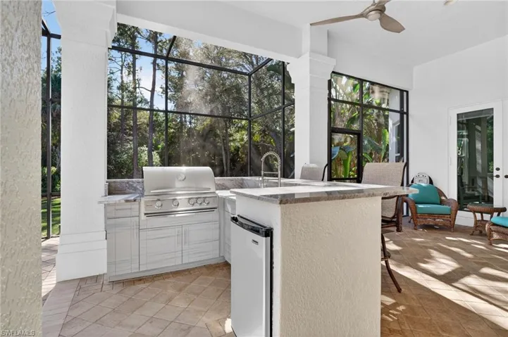 View of patio featuring area for grilling, ceiling fan, glass enclosure, and a sunroom