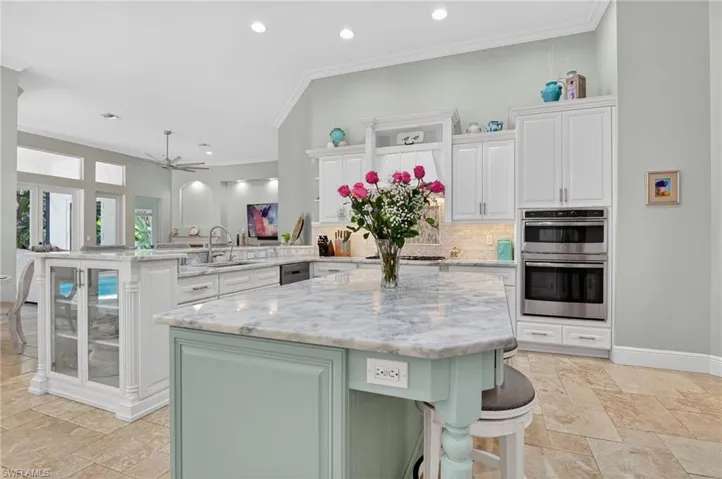 Kitchen featuring green cabinets, a kitchen breakfast bar, crown molding, white cabinets, and a peninsula