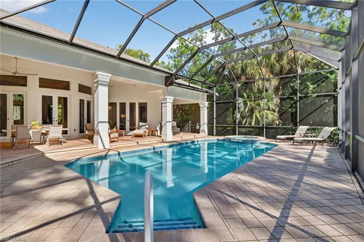 View of pool with a patio, glass enclosure, a pool with connected hot tub, and a sunroom