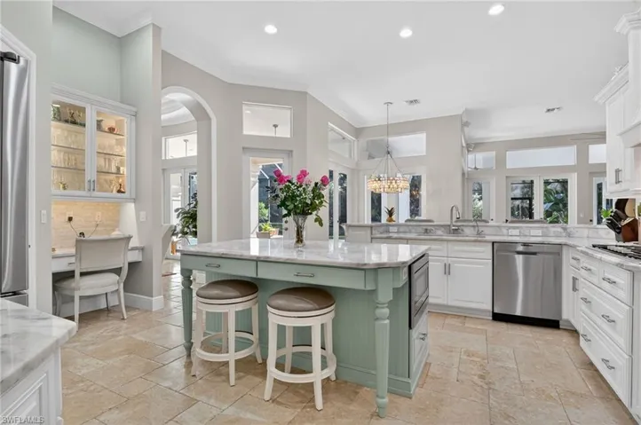 Kitchen with white cabinetry, a chandelier, a breakfast bar area, stone tile floors, and recessed lighting
